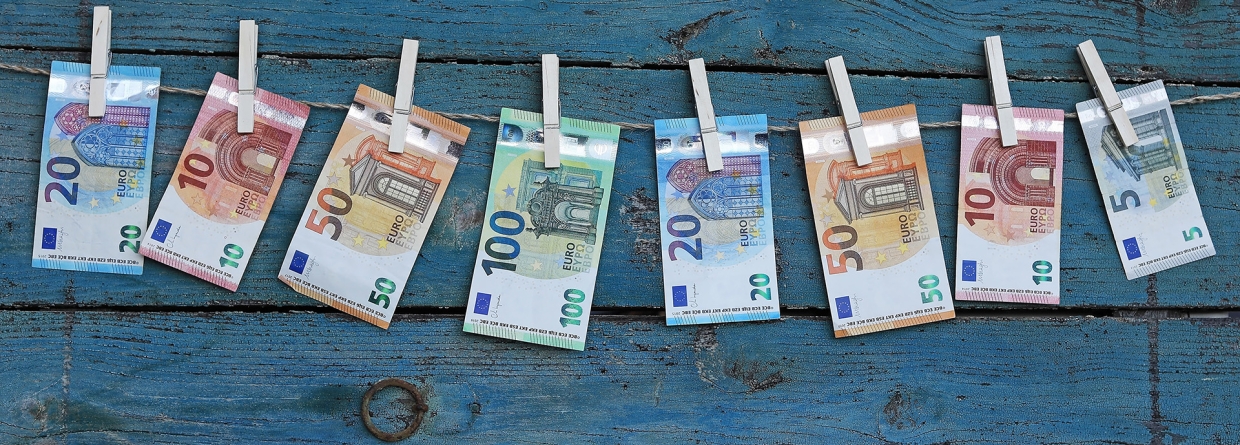 Verschillende euro biljetten hangen aan een waslijn met wasknijpers